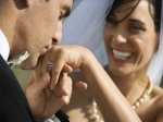 Caucasian prime adult male groom kissing hand of female bride.